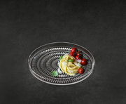 Glasierter Teller mit dekorativem Muster, von oben fotografiert, mit Pasta und Tomaten garniert.