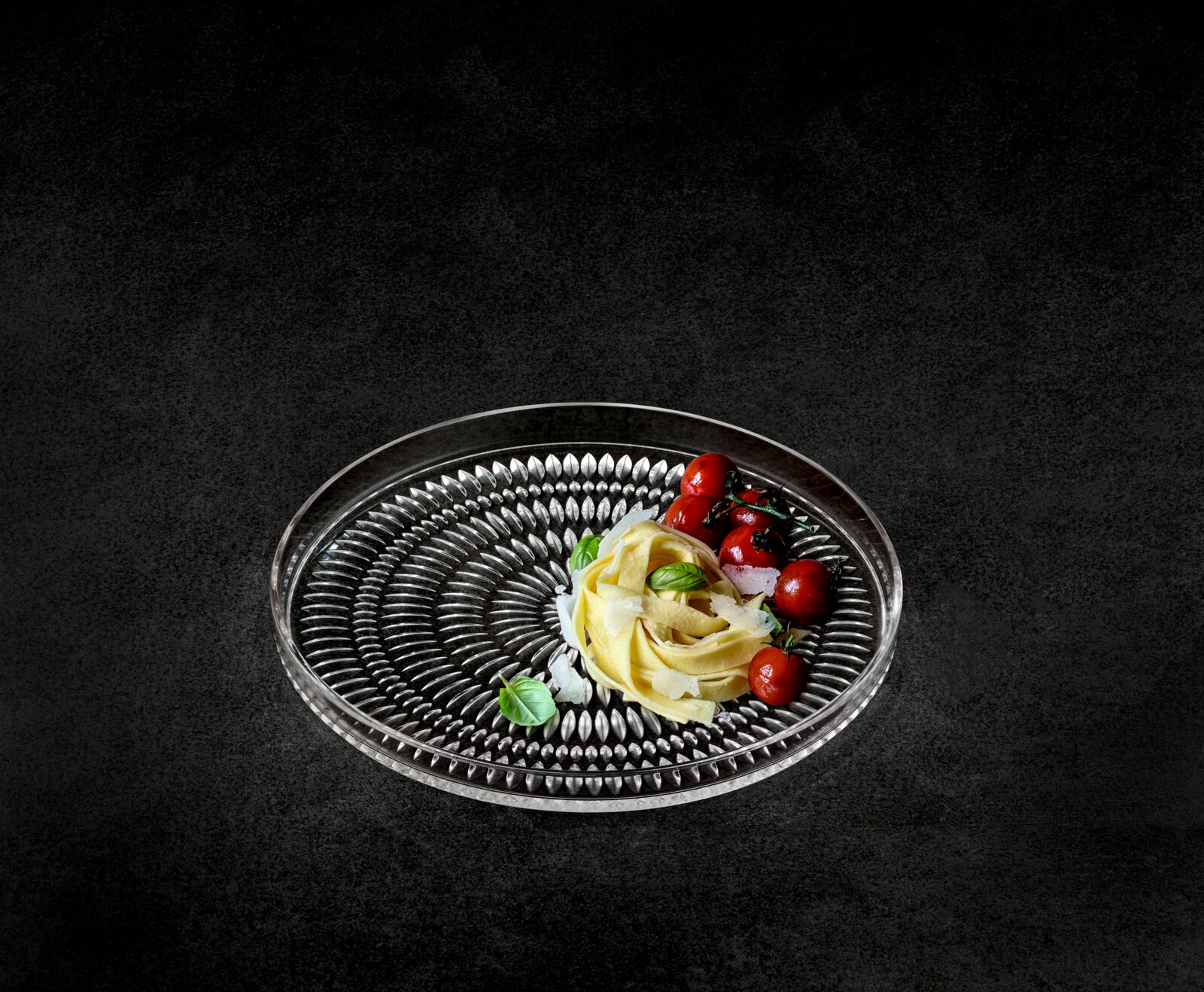 Glasierter Teller mit dekorativem Muster, von oben fotografiert, mit Pasta und Tomaten garniert.