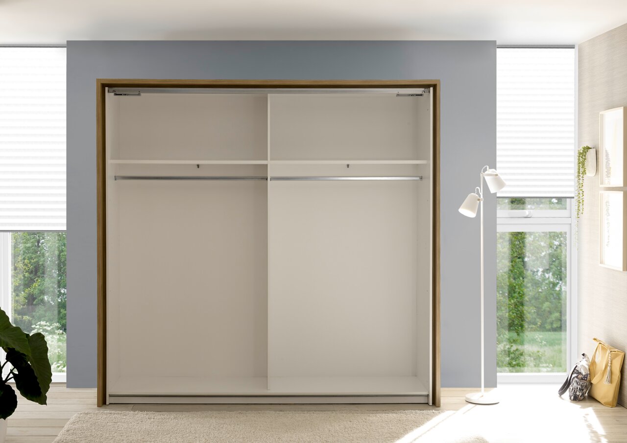 Offener Kleiderschrank im Schlafzimmer mit zwei Kleiderstangen und zwei Regalfächern, frontal betrachtet.