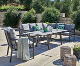 Lounge-Set im Freien mit grauen Kissen, Tisch und dekorativen Elementen, seitliche Perspektive