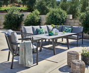 Lounge-Set im Freien mit grauen Kissen, Tisch und dekorativen Elementen, seitliche Perspektive