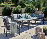 Lounge-Set im Freien mit grauen Kissen, Tisch und dekorativen Elementen, seitliche Perspektive