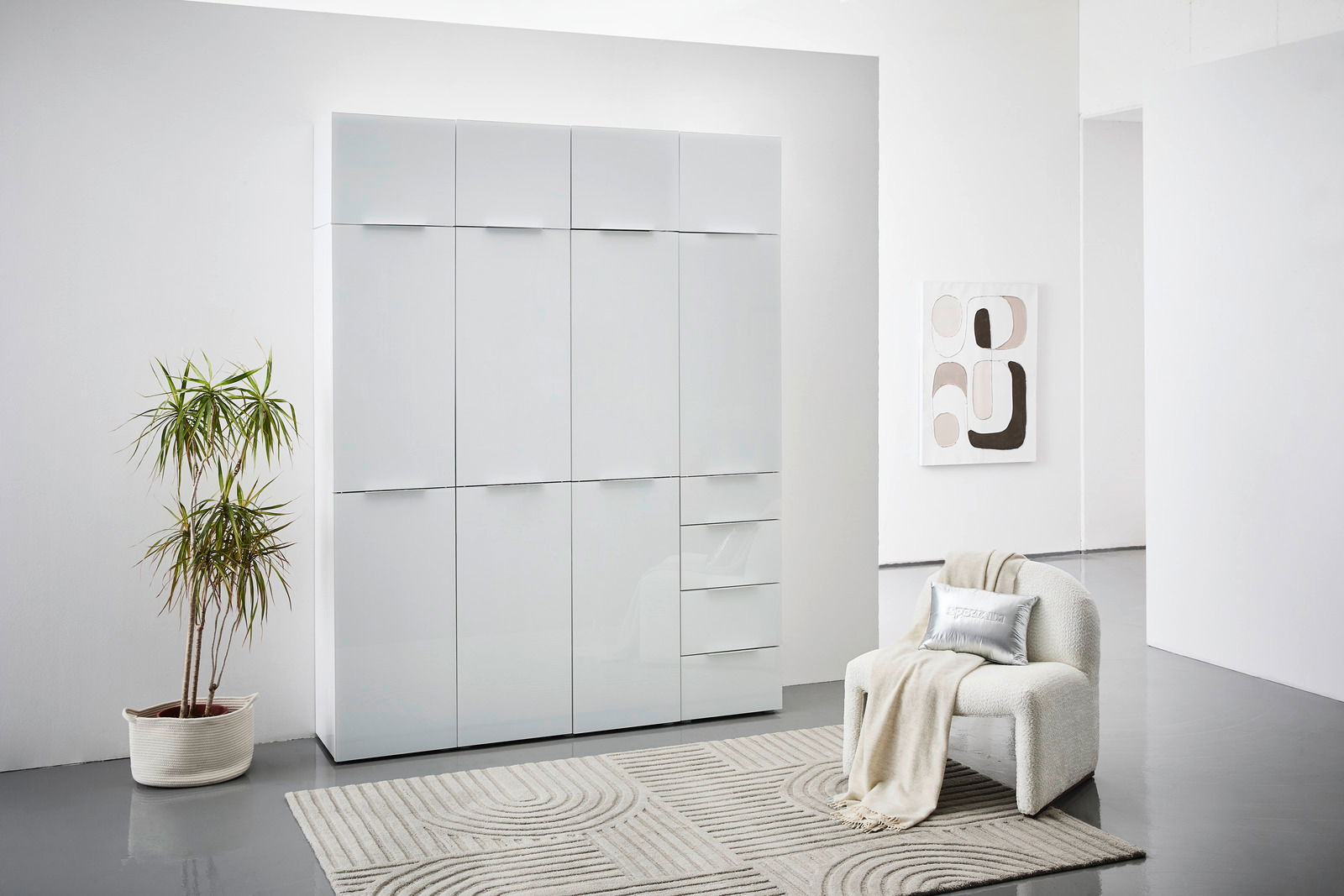 Moderner Mehrzweckschrank mit glänzender Oberfläche, frontal fotografiert in einem stilvoll eingerichteten Raum mit Pflanze und Sessel.