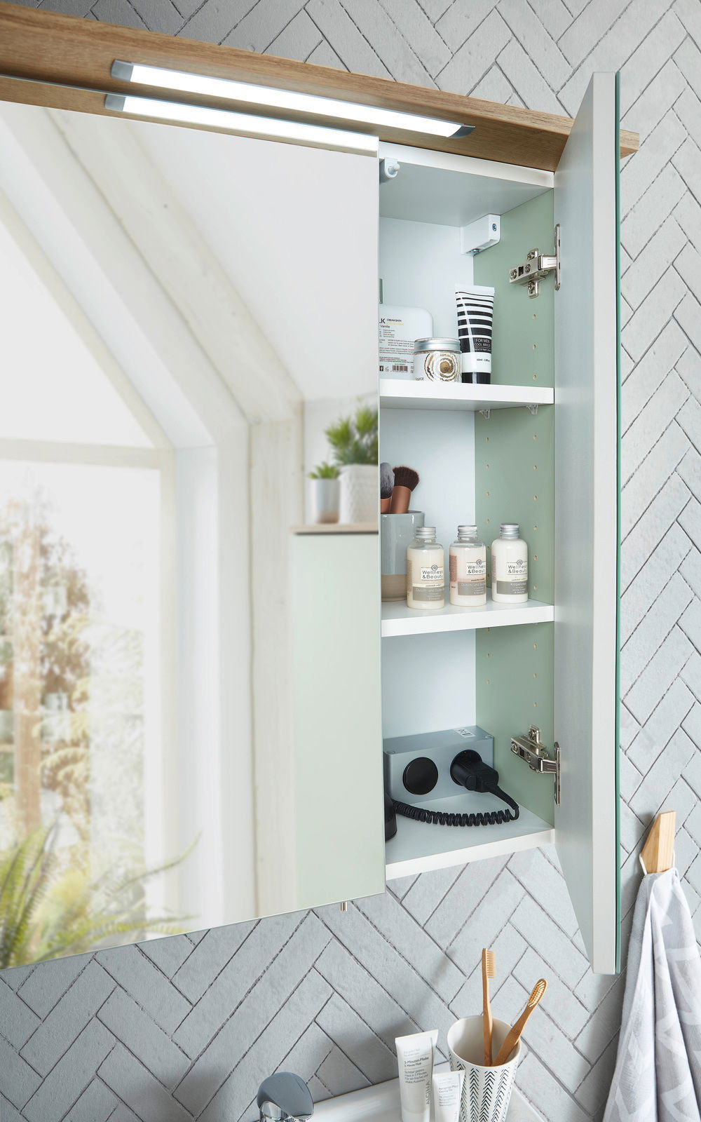 Moderner Spiegelschrank mit geöffneter Tür, der Innenraum zeigt Regale mit Pflegeprodukten und Steckdosen, seitliche Perspektive.