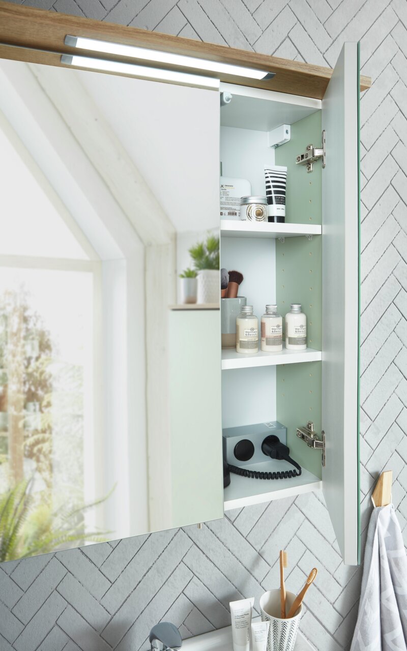 Moderner Spiegelschrank mit geöffneter Tür, der Innenraum zeigt Regale mit Pflegeprodukten und Steckdosen, seitliche Perspektive.