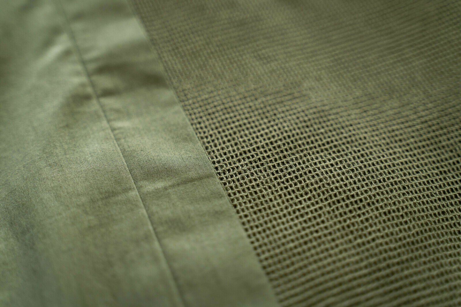 Nahaufnahme einer olivgrünen Bettwäsche mit strukturiertem Muster und glatter Oberfläche, von oben betrachtet.
