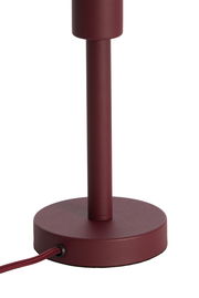 Nahaufnahme eines weinroten Lampenfußes mit rundem Sockel und Kabel, seitliche Perspektive.
