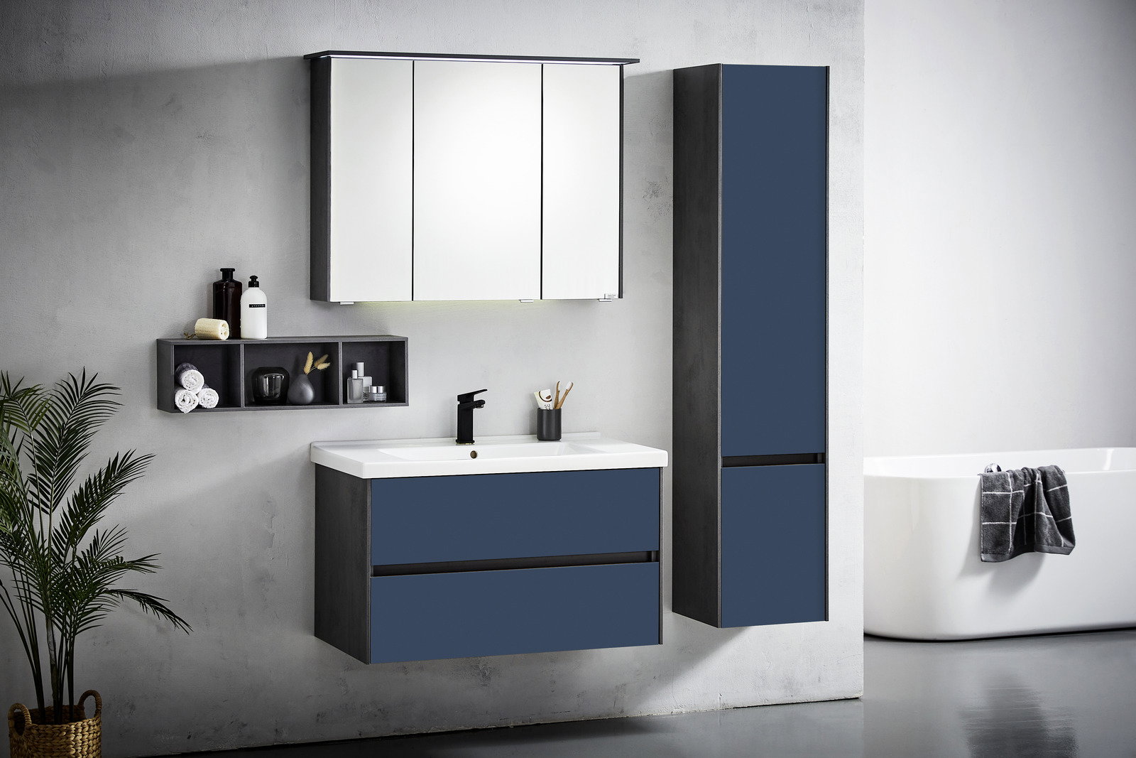 Moderne Badkombination in Dunkelblau mit Spiegelschrank, Waschbeckenunterschrank und hohem Schrank, seitliche Perspektive.