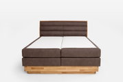 Vooraanzicht van een boxspringbed met een bruin gestoffeerd hoofdeinde en een houten frame.