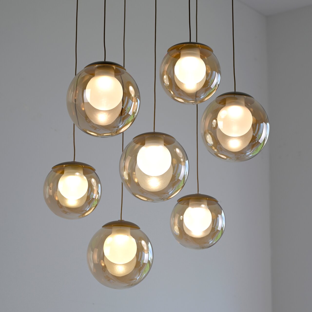 Moderne LED-Pendelleuchte mit sieben kugelförmigen, transparenten Lampenschirmen, von unten betrachtet.