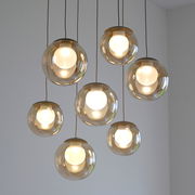 Moderne LED-Pendelleuchte mit sieben kugelförmigen, transparenten Lampenschirmen, von unten betrachtet.