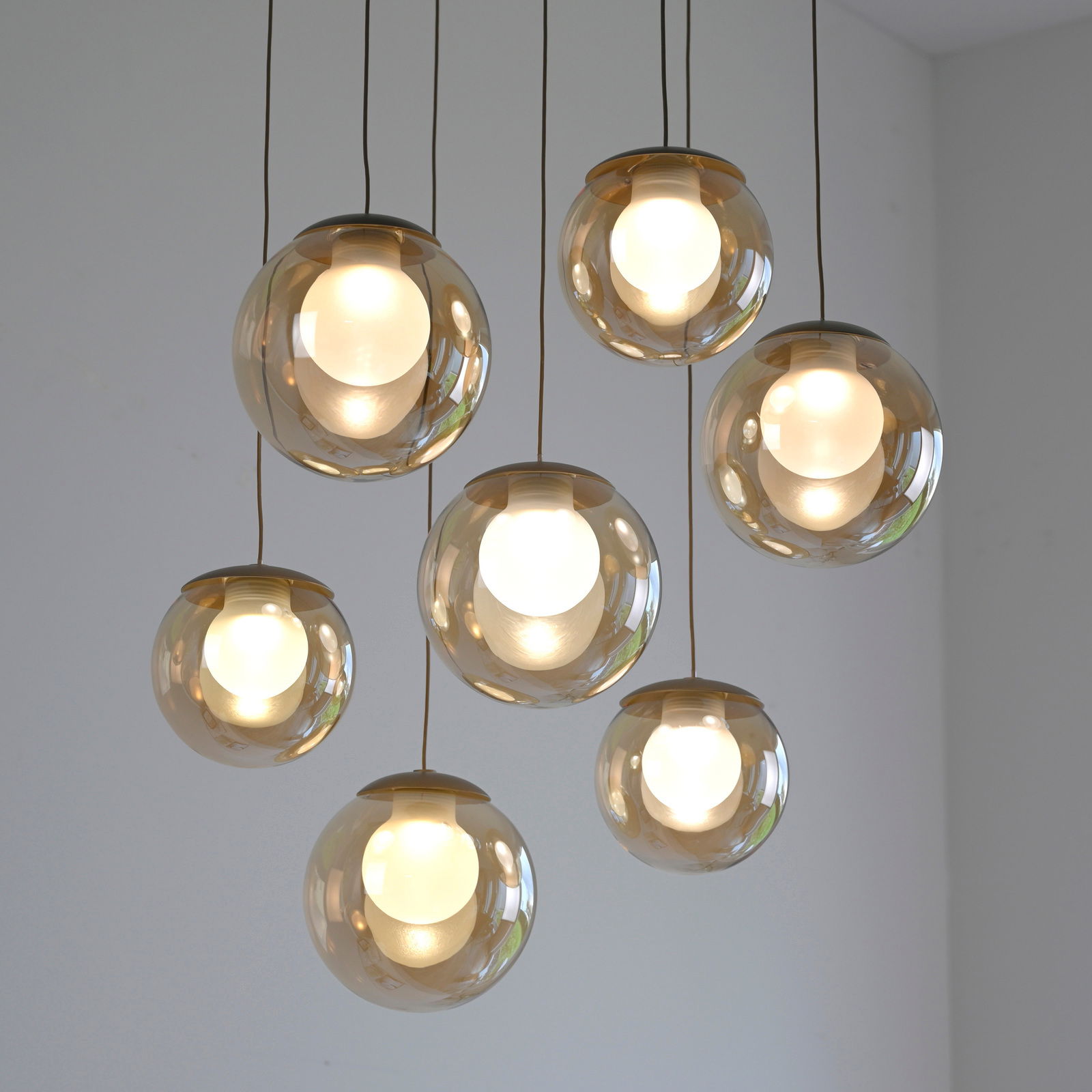 Moderne LED-Pendelleuchte mit sieben kugelförmigen, transparenten Lampenschirmen, von unten betrachtet.