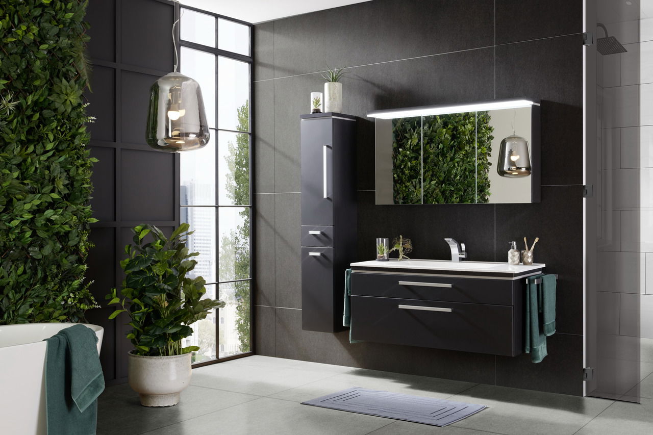 Moderne Badkombination mit dunklen Schränken und Spiegel, umgeben von grünen Pflanzen, aus seitlicher Perspektive fotografiert.