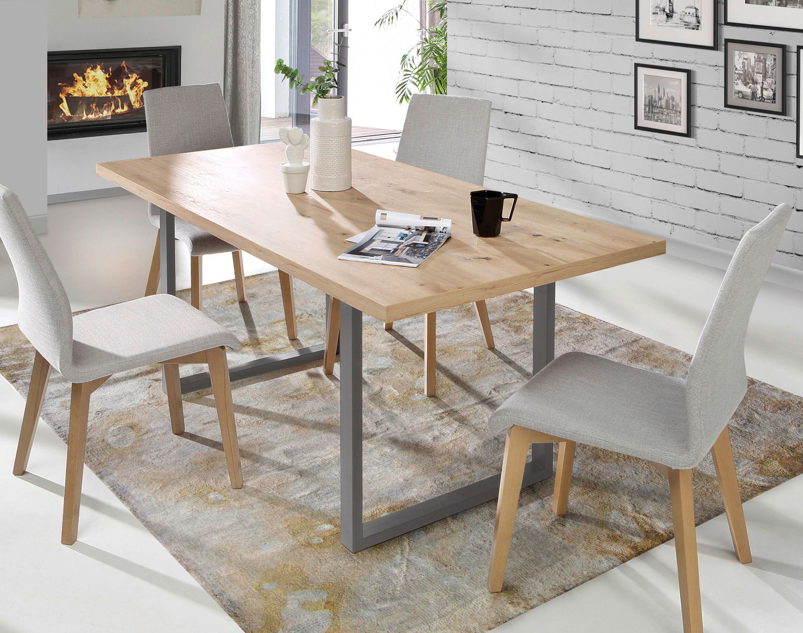 Moderner Esstisch aus Holz mit Metallgestell, umgeben von vier grauen Stühlen, in einem stilvoll eingerichteten Raum mit Kamin und Wandbildern, aus seitlicher Perspektive fotografiert.