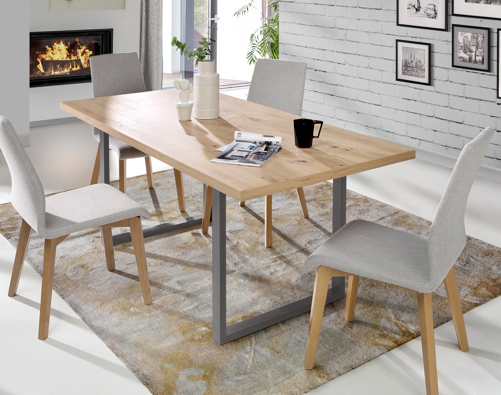 Moderner Esstisch aus Holz mit Metallgestell, umgeben von vier grauen Stühlen, in einem stilvoll eingerichteten Raum mit Kamin und Wandbildern, aus seitlicher Perspektive fotografiert.