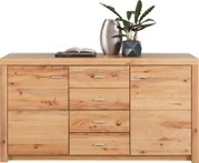 Vooraanzicht van een brede houten dressoir/commode met natuurlijke nerf en knoesten, vier centrale lades met metalen grepen en twee zijdeuren, met vaas, boek en plant bovenop tegen witte achtergrond