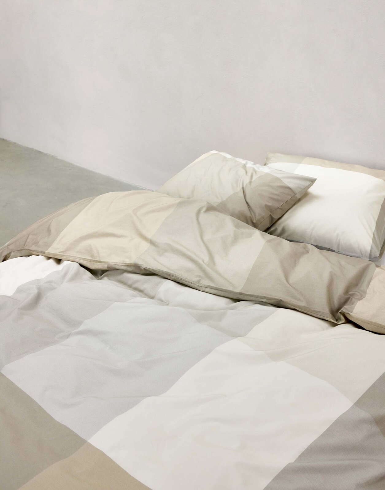 Beddengoedset in beige- en grijstinten op een bed, zijaanzicht