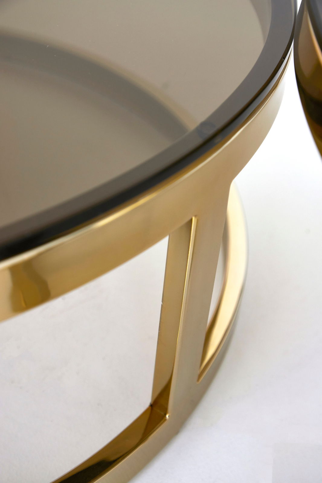 Nahaufnahme eines Couchtisches mit goldfarbenem Metallrahmen und getönter Glasplatte, seitliche Perspektive.