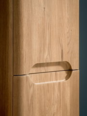 Detailaufnahme aus schräger Seitenperspektive: integrierter Griffausschnitt an einer hellen Holz-Schranktür mit sichtbarer Maserung