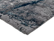 Nahaufnahme eines modernen Teppichs mit grauen und blauen Mustern, perspektivisch von der Seite aufgenommen.