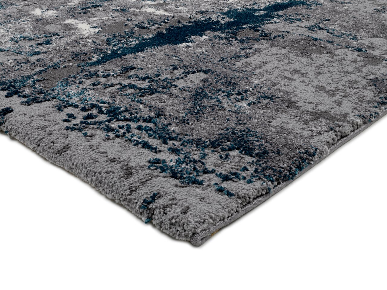 Nahaufnahme eines modernen Teppichs mit grauen und blauen Mustern, perspektivisch von der Seite aufgenommen.