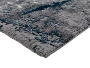 Nahaufnahme eines modernen Teppichs mit grauen und blauen Mustern, perspektivisch von der Seite aufgenommen.