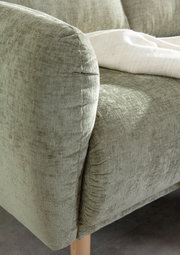 Nahaufnahme einer grünen Sofaecke mit weicher Polsterung und Holzbeinen, von der Seite betrachtet.
