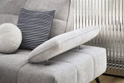 Close-up van een grijze longchair-set met verstelbare rugleuning en twee kussens, een gestreept en een rond, gezien vanaf de zijkant.