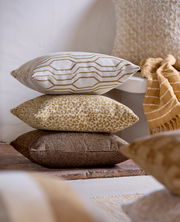 Drei dekorative Kissen in verschiedenen Mustern und Farben, gestapelt auf einem Boden, seitliche Perspektive.