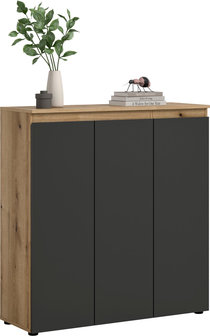 MID.YOU Universalschrank SCARPA Moderne Kommode mit Holzoptik-Korpus und drei mattschwarzen Türen, frontal aus leicht schräger Perspektive vor weißem Hintergrund, dekoriert mit Vase, Dose und Bücherstapel