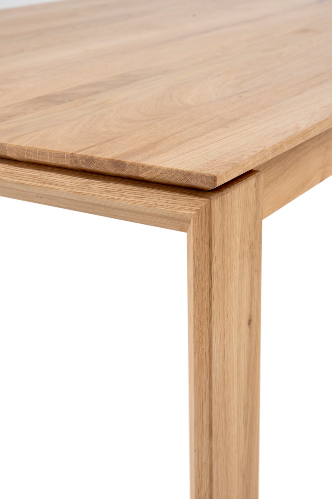 Detailaufnahme eines Holztisches aus hellem Massivholz mit sichtbarer Maserung, Ecke der Tischplatte und Tischbein aus schräger Seitenperspektive