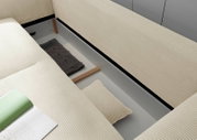 Detailfoto van een multifunctionele bank met geopende opbergruimte, beige gestreepte stof, gezien van bovenaf.