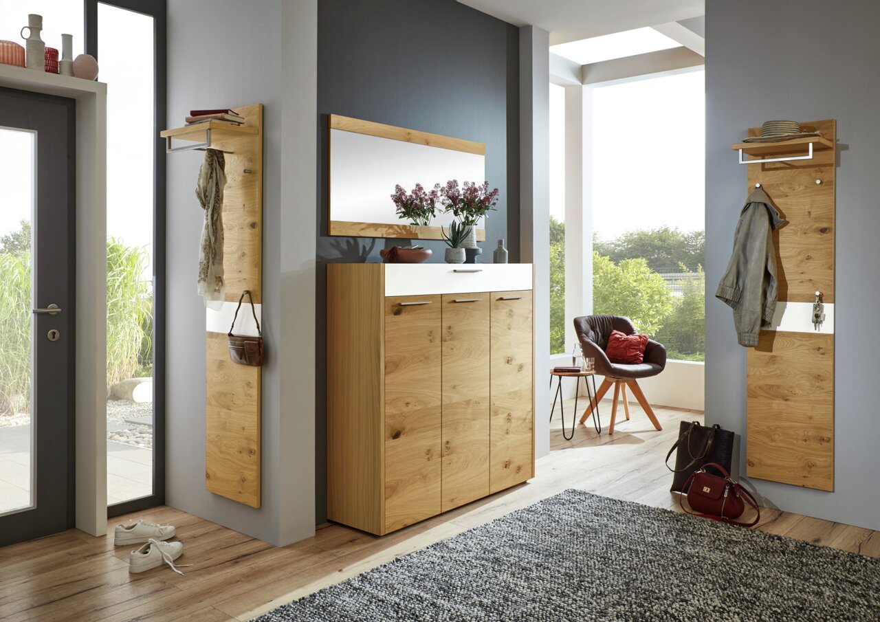 Moderner Eingangsbereich mit Holz-Garderobenpaneelen, einem Spiegel und einem Sitzkissen auf einem Stuhl, aus der Perspektive des Raumes fotografiert.