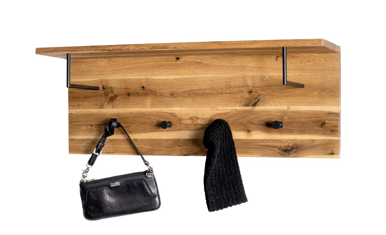 Wandgarderobe aus massivem Holz mit Ablage, zwei Metallhaken und zwei runden Wandknöpfen, frontal aus leicht erhöhter Perspektive fotografiert; daran hängen eine schwarze Handtasche und ein dunkler Schal.