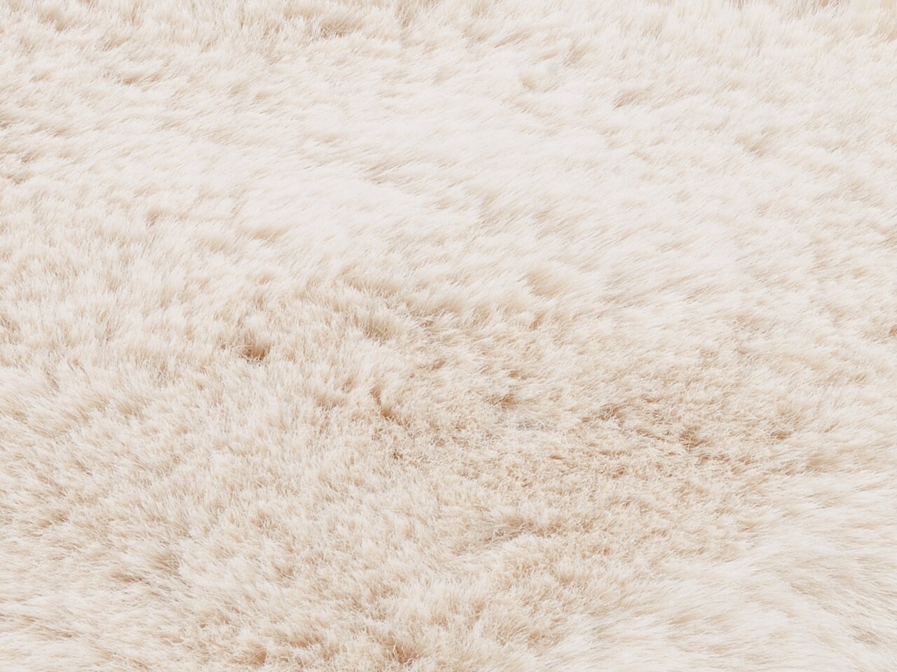 Nahaufnahme eines weichen, flauschigen Fellteppichs in cremeweißer Farbe, von oben betrachtet.