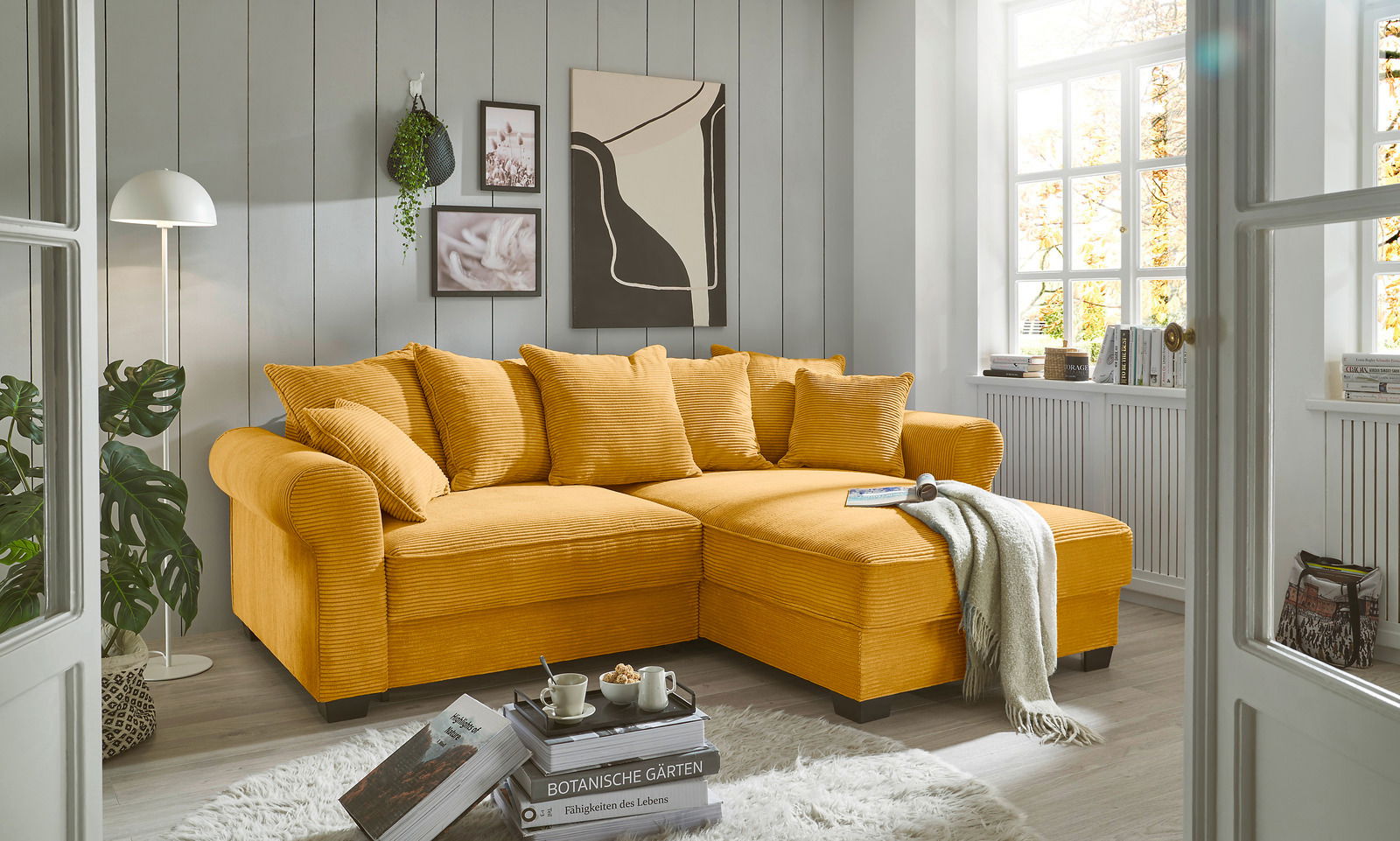 Hom´in Ecksofa MAUREEN Gemütliche gelbe Rundecke in einem hellen Wohnzimmer, seitliche Perspektive.