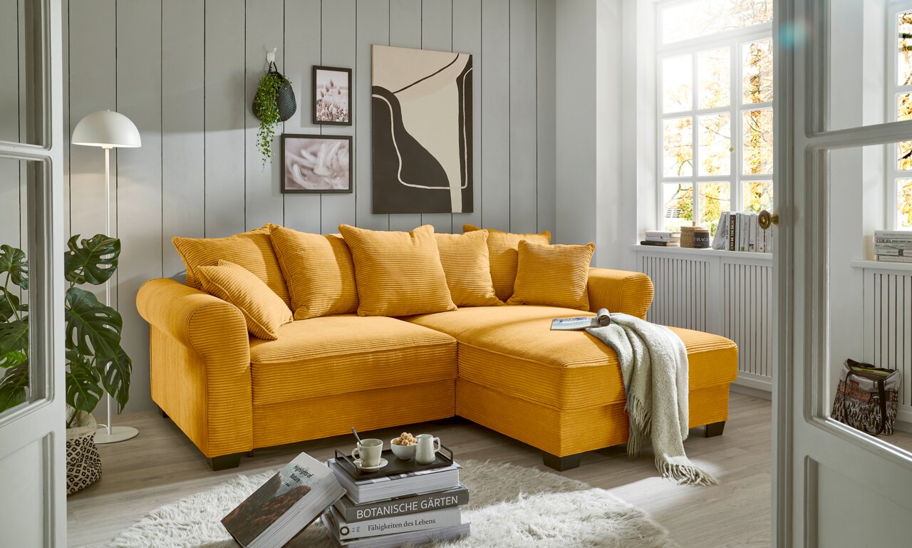 Hom´in Ecksofa MAUREEN Gemütliche gelbe Rundecke in einem hellen Wohnzimmer, seitliche Perspektive.