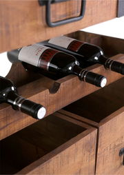 Nahaufnahme eines Servierwagens aus Holz mit integrierten Weinregalen, die mehrere Weinflaschen halten. Perspektive von vorne.