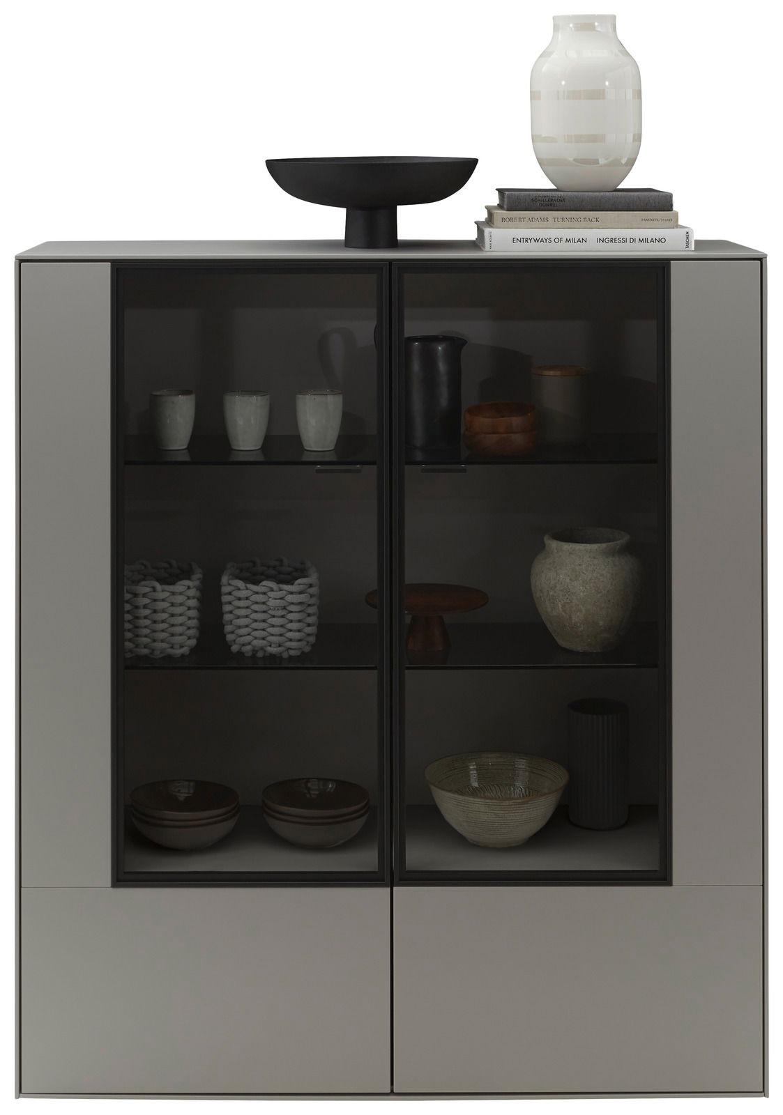 Modernes Highboard mit Glasfronten, dekoriert mit Keramik und Büchern, aus frontaler Perspektive.