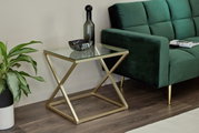 Moderner Beistelltisch mit Glasplatte und goldfarbenem Metallgestell, seitliche Perspektive neben einem grünen Sofa.