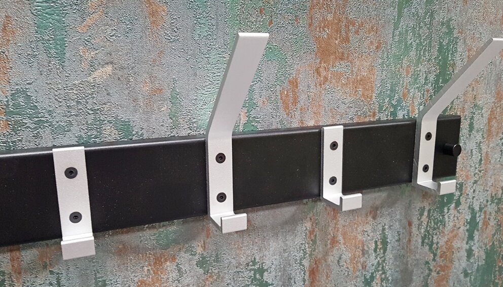 Zurbrüggen Garderobenleiste 7 Wandgarderobe mit schwarzer Leiste und vier silbernen Metallhaken an einer strukturierten Wand, Perspektive: frontale Ansicht leicht von links