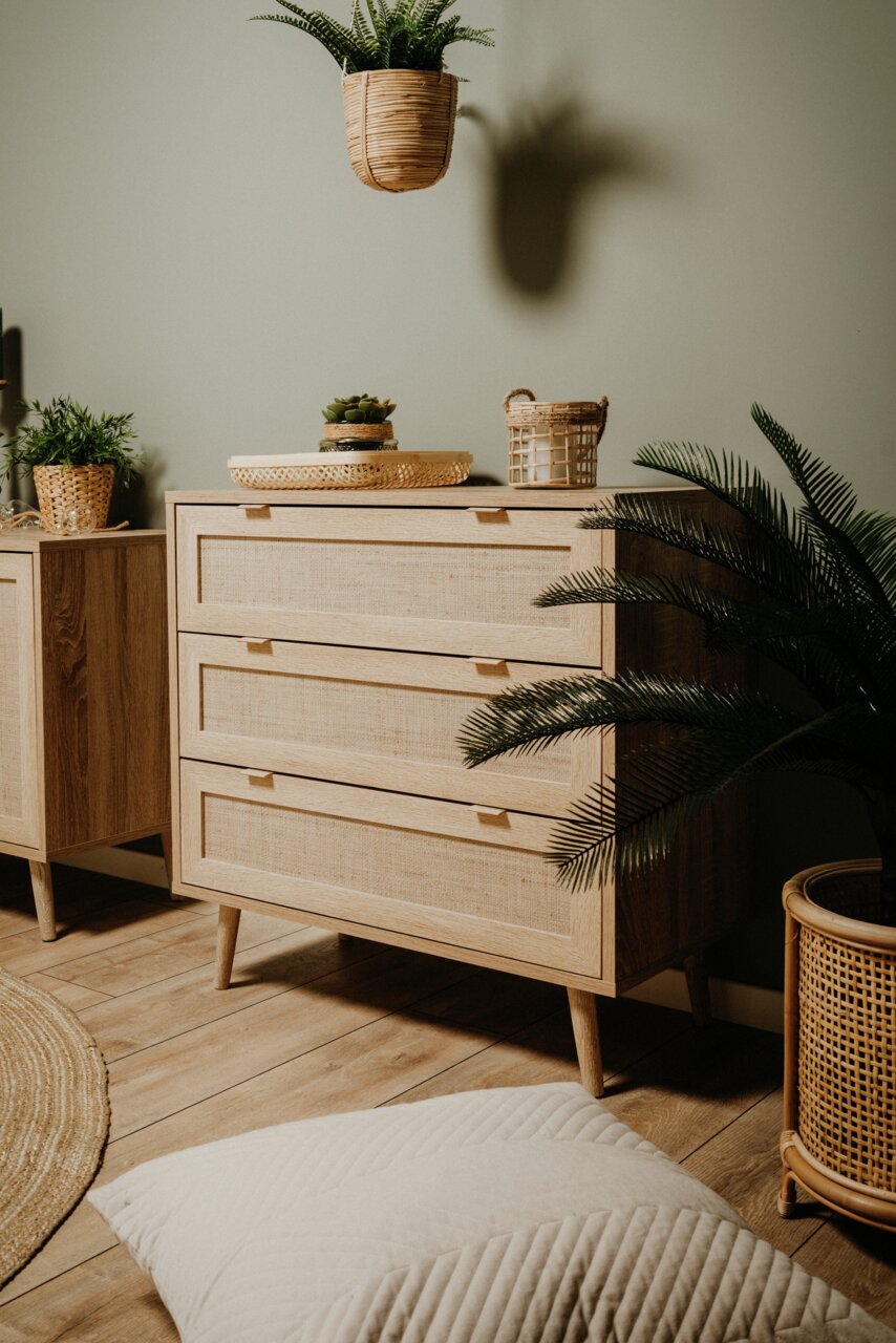 Houten drielade dressoir, versierd met planten, gefotografeerd vanuit een zijaanzicht.