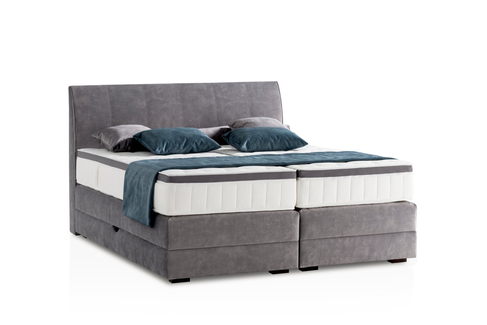 Graues Boxspringbett mit Kopfteil, seitliche Perspektive, dekoriert mit blauen und grauen Kissen.