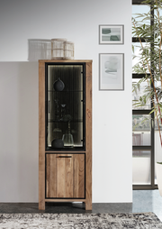 Vitrine aus Holz mit Glastür, dekoriert mit Vasen und Gläsern, frontal fotografiert.