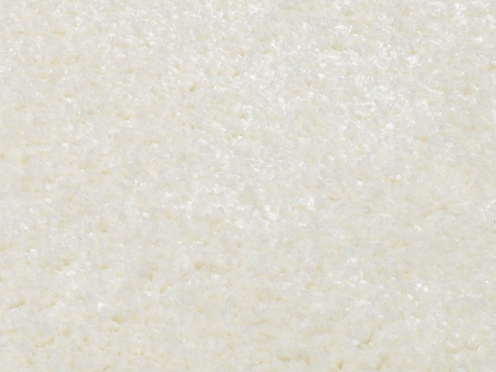 Nahaufnahme eines cremeweißen Uni-Teppichs mit weicher, flauschiger Textur.
