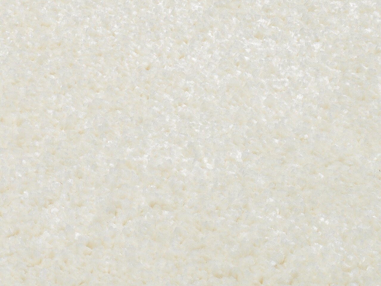 Nahaufnahme eines cremeweißen Uni-Teppichs mit weicher, flauschiger Textur.