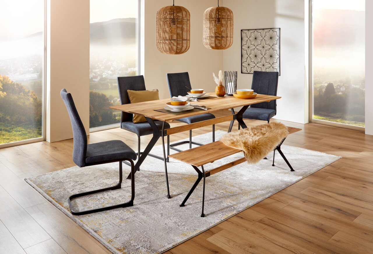 Z2 Bank KÖLN Esszimmer mit modernem Esstisch und Bank aus Holz und Metall, umgeben von stilvollen Stühlen, aus der Perspektive eines hellen, gemütlichen Raumes mit großen Fenstern.