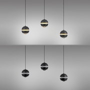 Mehrere moderne, kugelförmige Pendelleuchten in Schwarz mit umlaufendem Lichtband und Glasunterteil, frontal in leichter Untersicht vor grauem Hintergrund
