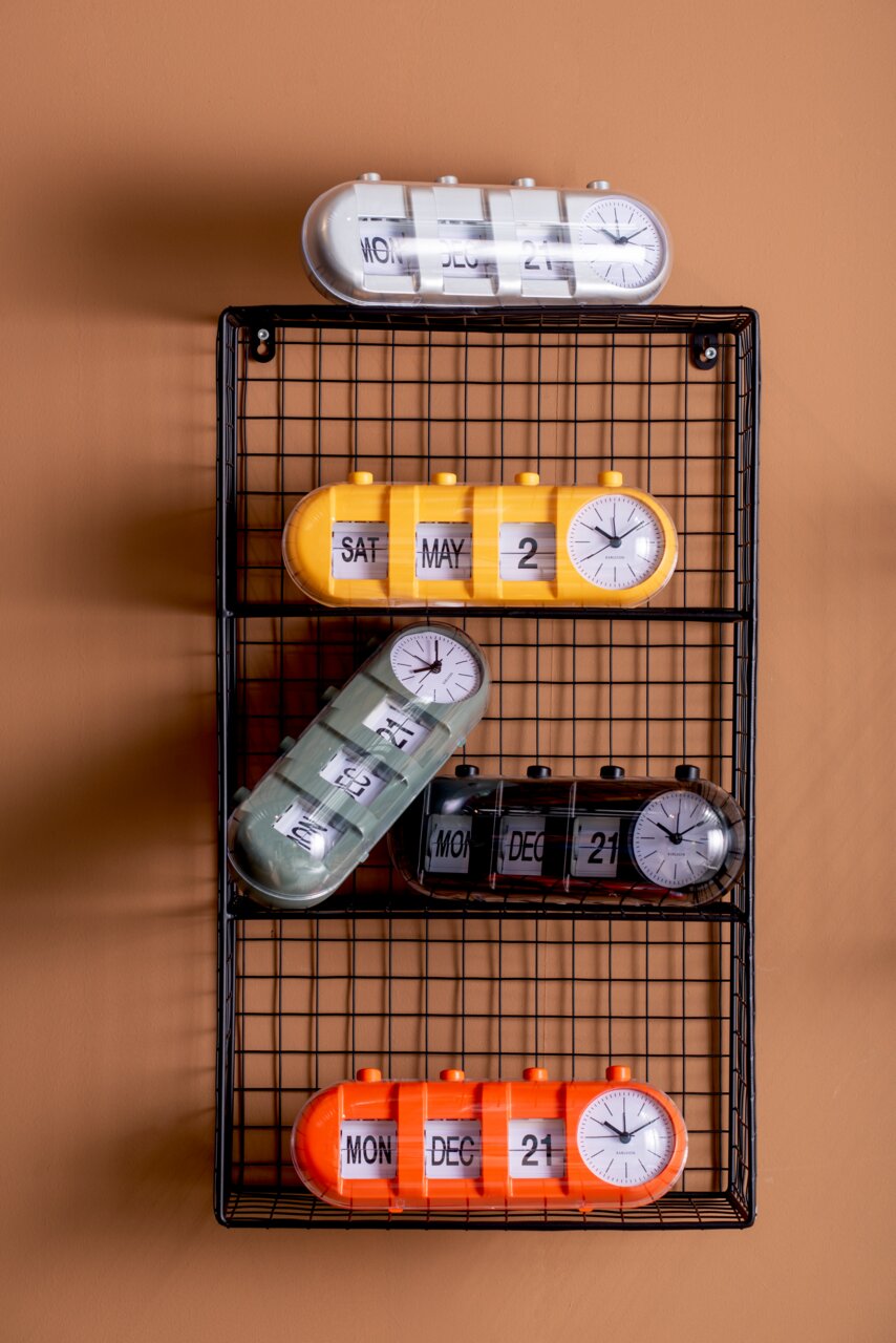 KARLSSON Tischuhr Kalender Flip RETRO Verschiedene Tischuhren mit Kalenderfunktion in bunten Farben auf einem Gitterregal, seitliche Perspektive.