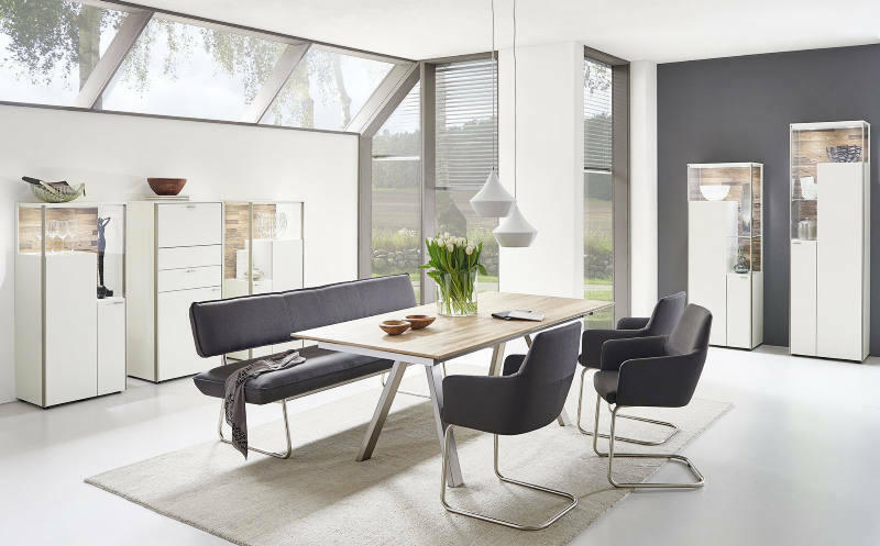 Moderner Esstisch mit Holzplatte und Metallbeinen, umgeben von stilvollen Stühlen und einer Bank, in einem hellen, eleganten Raum mit großen Fenstern. Perspektive: Frontalansicht.